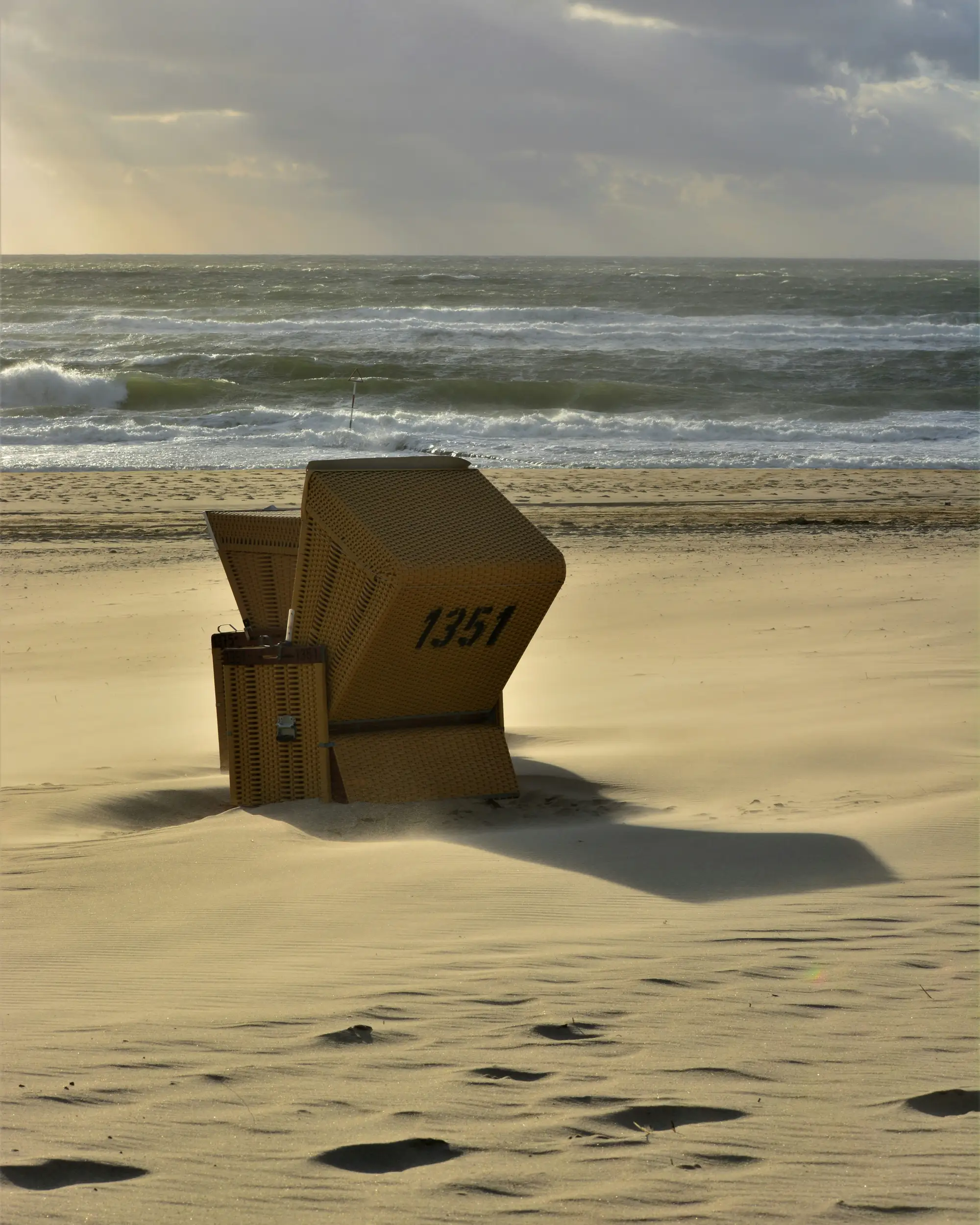 A hooded beach chair in the drifting sand before the Baltic surf