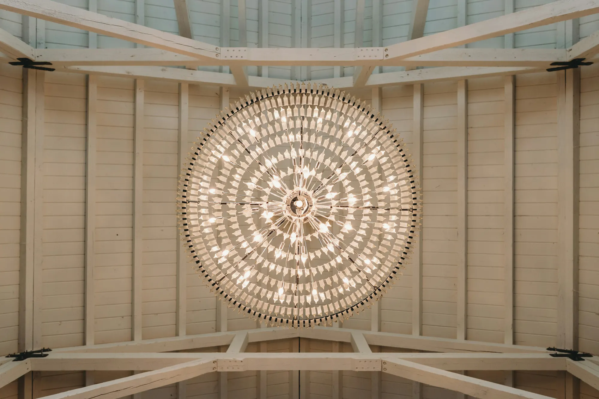 A round chandelier beneath the white timber ceiling of the hall