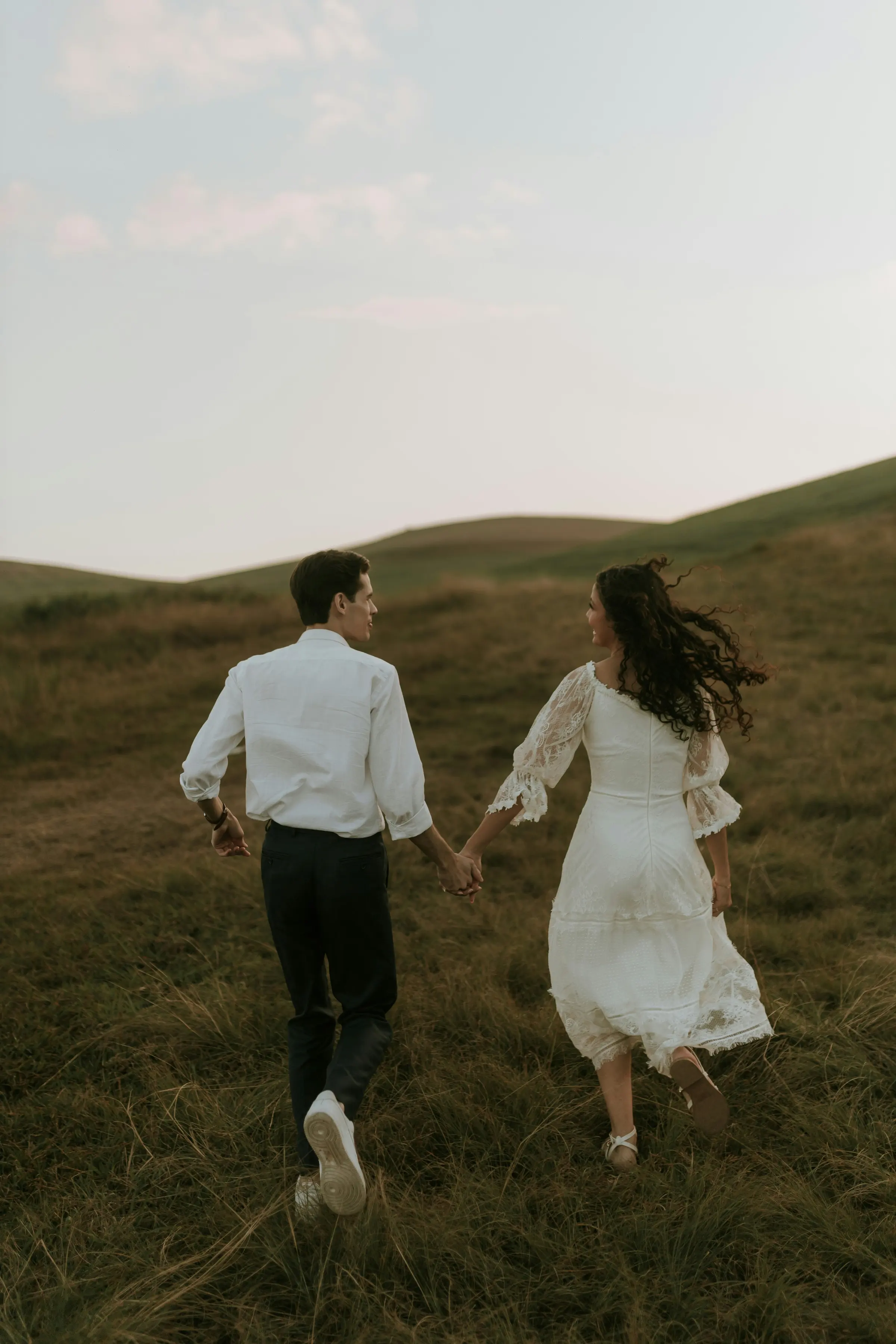 Oliver and Marie walking hand in hand through the dune grass