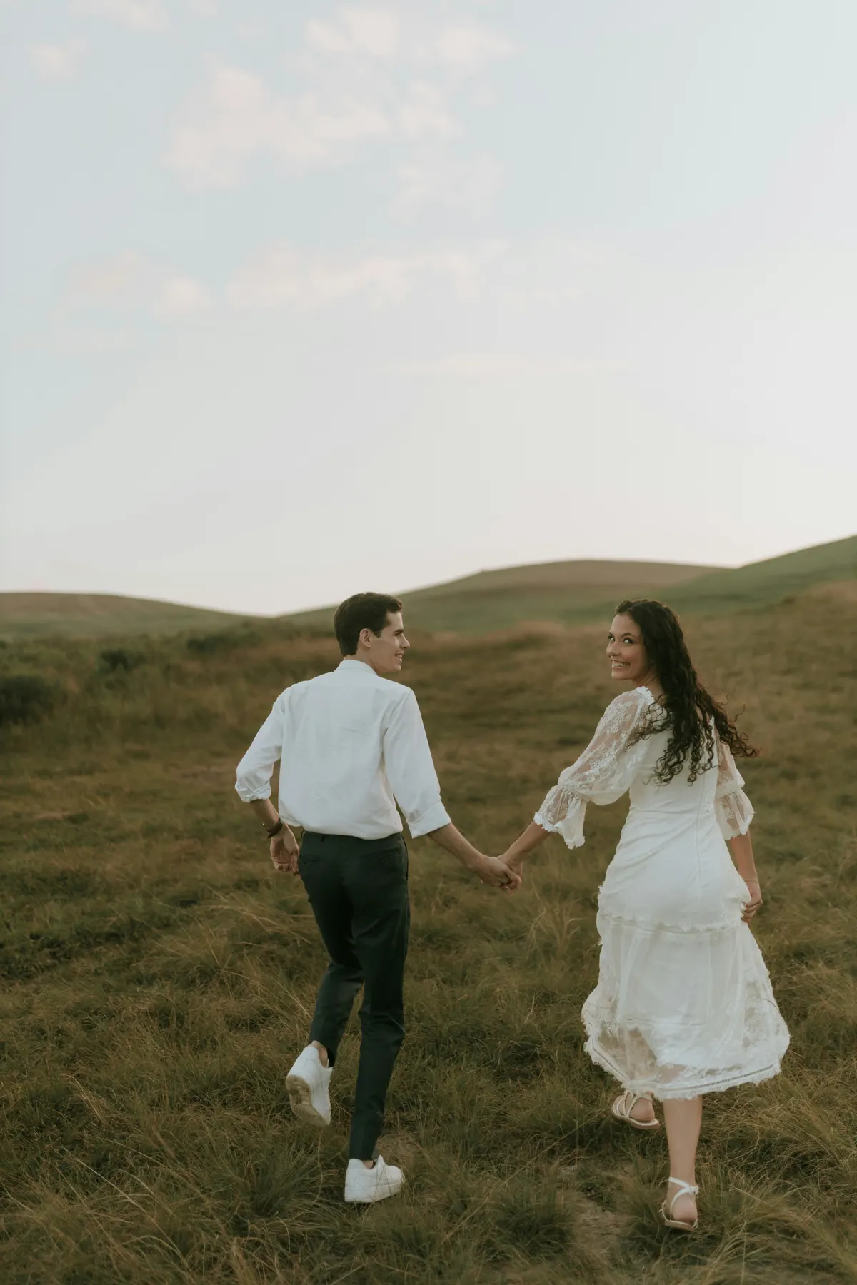 Oliver and Marie walking hand in hand through the meadow