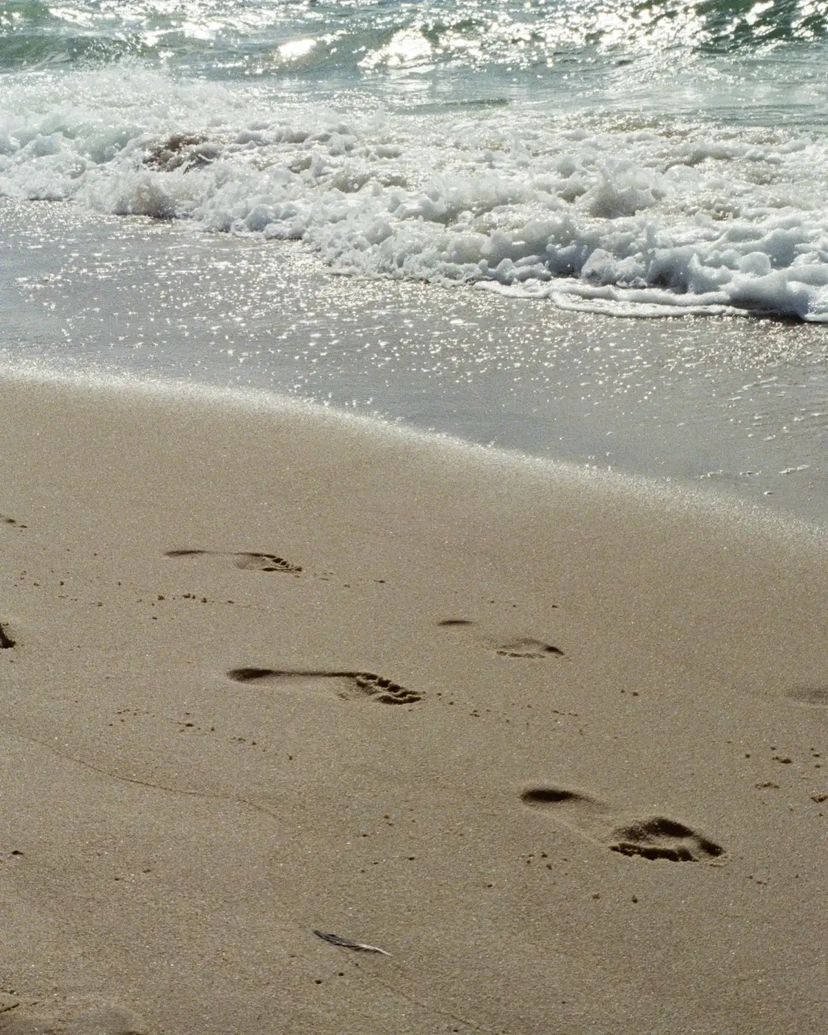 A wide sandy beach with the line of the surf